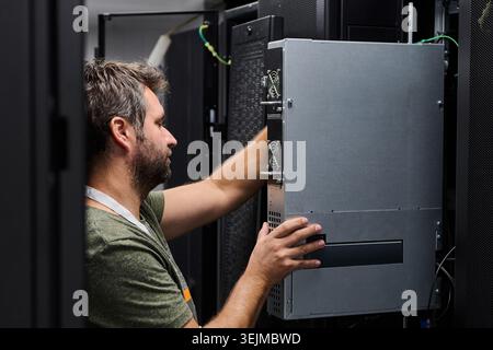 IT technician installing server hardware in a data center during routine maintenance and system upgrade Stock Photo