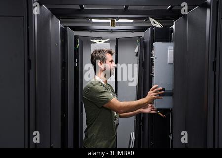 Data center technician installing server hardware in a server rack performing IT maintenance Stock Photo