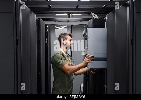 Data center technician installing and maintaining servers in a modern server rack Stock Photo