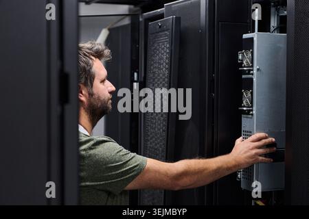 It technician performing server maintenance in a data center server rack with focused attention Stock Photo