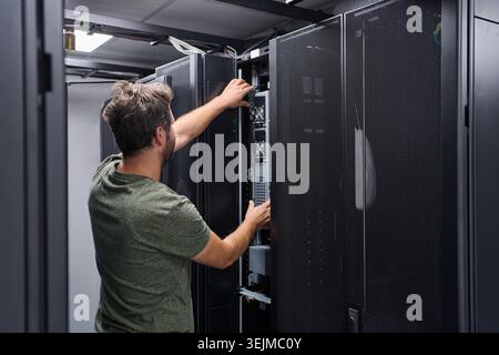 Data center technician servicing server rack in a modern IT infrastructure room Stock Photo
