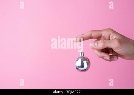 Shiny christmas ball hanging on woman finger, christmas decorations Stock Photo