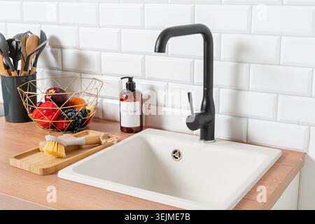 Kitchen sink on wooden countertop, white brick wall and black faucet Stock Photo