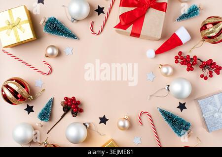 Christmas background with decorations, frame made of gifts, candy canes, balls and trees on beige background, flat lay Stock Photo