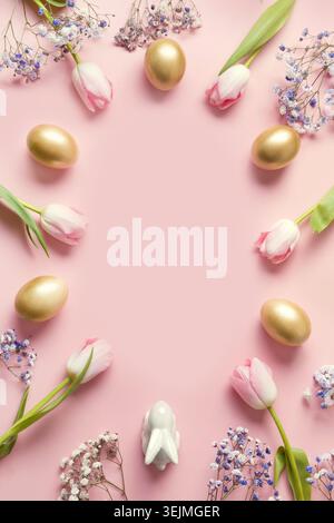 Easter frame of pink tulips, golden eggs and bunny on pastel pink. Stock Photo