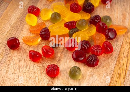 Fruit gummy candy pile close up, vegan chewing marmalade pills, jelly gumdrops heap, colorful gelatin candies macro set on wood background Stock Photo