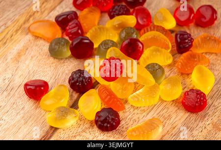 Fruit gummy candy pile close up, vegan chewing marmalade pills, jelly gumdrops heap, colorful gelatin candies macro set on wood background Stock Photo