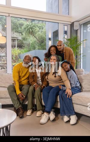 African American multigenerational family posing on light sectional sofa in modern living room. Portrait, togetherness, home, garden, sunlit, calm, wa Stock Photo