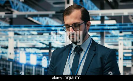 Monitoring system, AR simulation and engineer portrait in data center, identifying performance bottlenecks. Implementing optimizations, VFX compositing and worker in server farm using device, camera B Stock Photo