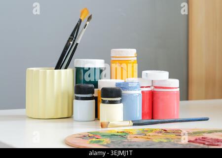 Variety of colorful kids school supplies, colorful paint cans for kid drawing and painting on white desk Stock Photo