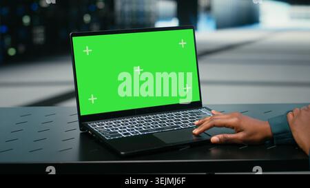 Green screen laptop, debugging system errors and technician in data center uses AR tech visualization. Running diagnostics, mockup notebook and expert in server farm with wireframe mesh gear, camera B Stock Photo
