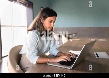 Focused woman office employee working on laptop in workplace Stock Photo
