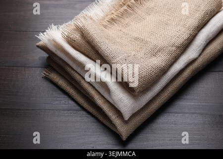 Folded natural burlap fabrics on wooden table, closeup Stock Photo