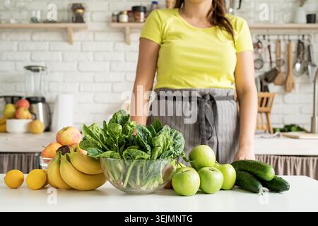 Close up of table with green vegetables and fresh fruit in the kitchen Stock Photo