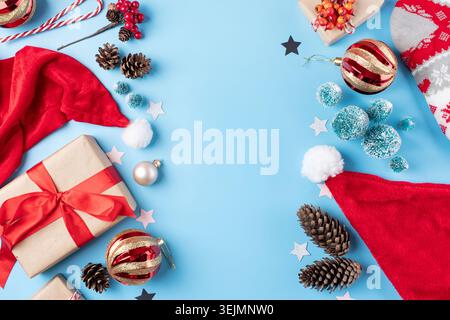 Christmas background with decorations, frame made of gifts, candy canes, balls and trees on blue background, flat lay Stock Photo
