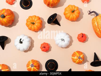 Pattern of colorful artificial pumpkins and halloween hats on orange background Stock Photo
