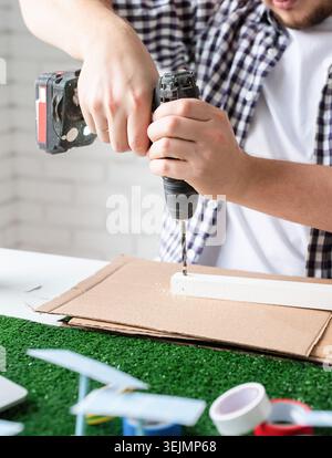Young man making renewable energy project dummy using drill Stock Photo