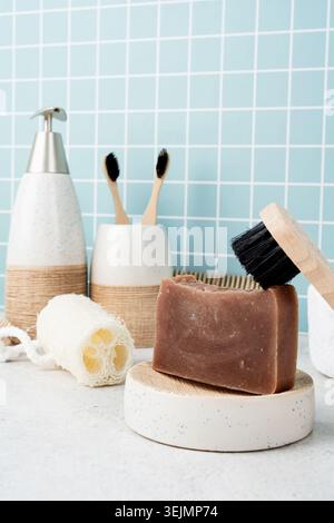 Bath accessories with bamboo brushes, handmade soap, dispenser and natural brushes on bath shelf Stock Photo