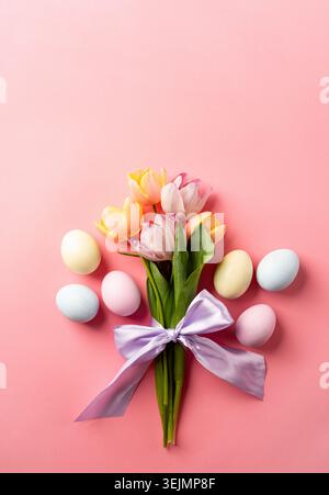Easter background with eggs and tulips on pink backdrop, top view flat lay Stock Photo