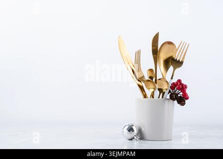 Set of cutlery of spoons, knives and forks in cup with holiday decorations on dining table, copy space Stock Photo