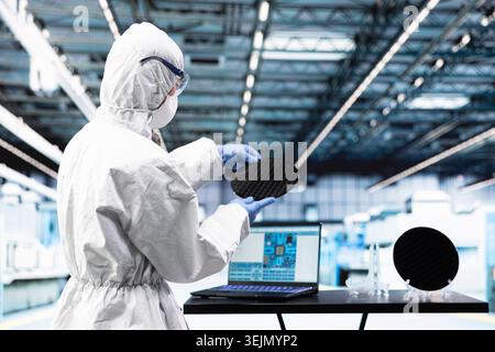Engineer man processing silicon wafer using EDA software in automated manufacturing facility. Technician inspecting delicate microelectronic hardware with laptop program during quality control process Stock Photo