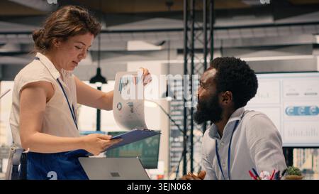 Diverse business team collaborating in modern corporate office, reviewing visual data, charts and KPI dashboards on laptop. Professionals discussing performance metrics and forecasting. Stock Photo