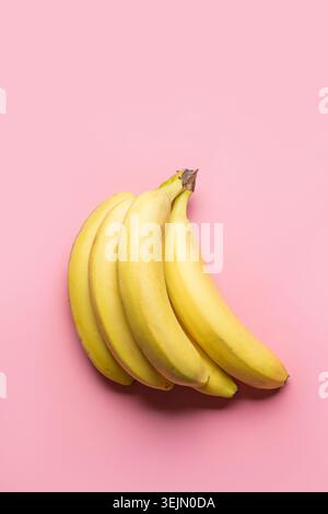 Bunch of ripe yellow bananas on pink background. Top view. Stock Photo