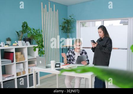 Two women sitting on the sofa in small office talking Stock Photo