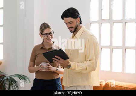 Colleagues collaborating on digital tablet in modern office Stock Photo