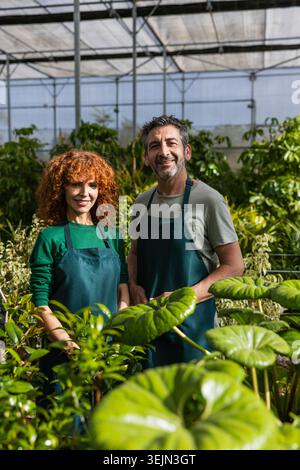 Garden center workers smiling inside plant nursery greenhouse Stock Photo