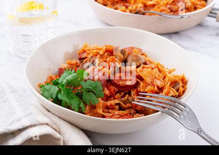Bigos, Polish dish bigos, on the table, pan with stewed meat, with cabbage, chorizo sausages, mushrooms, homemade, without peopl Stock Photo