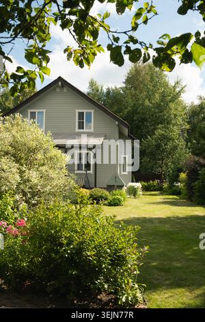Contemporary two-story house of timber in countryside in summer with shrubs Stock Photo