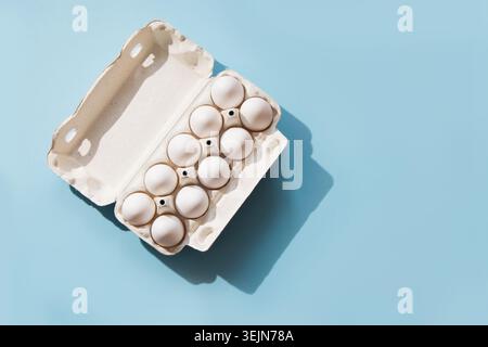 White eggs in the package on blue. Top view. Stock Photo
