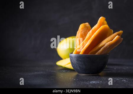 Fresh and dried mango chips on black. Close up. Stock Photo