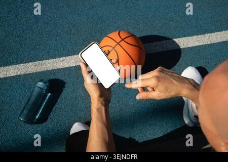Basketball player using smartphone and social media during game interval. Sports mock up. View from above. Stock Photo