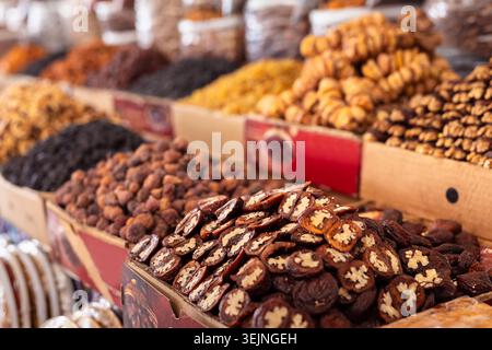 Dried fruits in heaps closeup at market stall. Stuffed dried apricots with walnuts. Raisins, walnuts vibrant dried fruits nuts o Stock Photo