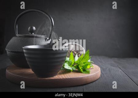 Cup tea with mint and kettle on dark background. Chinese tea concept. Stock Photo