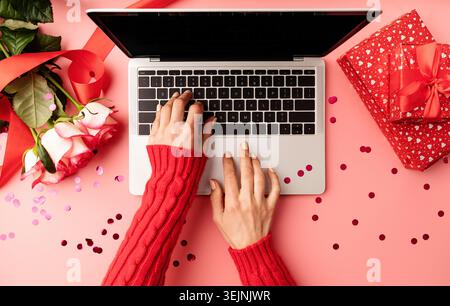 Female hands typing on the keyboard, top view on pink background Stock Photo