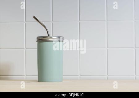 Reusable cup with metal straw on table Stock Photo