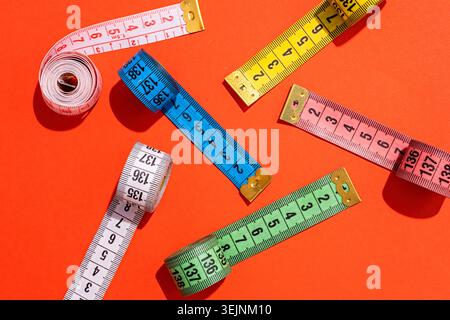 Colorful measuring tapes top view on bright red background Stock Photo