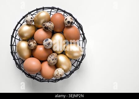 Easter golden, quail, chicken eggs in modern black bowl on white. Stock Photo