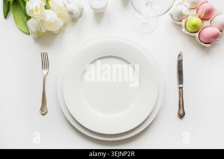 Easter table setting with white tulips, eggs on white table. Top view. Stock Photo