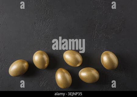 Chicken golden eggs on black. Easter dark concept. View from above. Stock Photo