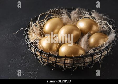 Chicken colored golden eggs in decorative vase on black. Easter dark concept. Stock Photo