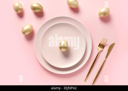 Easter table setting decorated golden eggs on pink. Stock Photo