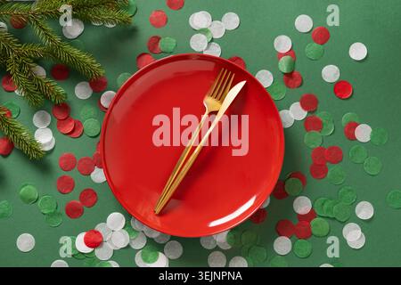 Christmas table setting with red empty plate on green. Xmas dinner. Stock Photo