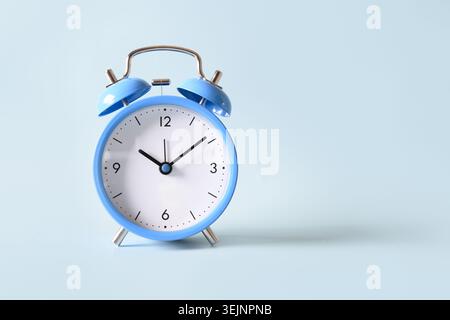 Old-fashioned blue alarm clock on blue background. Stock Photo