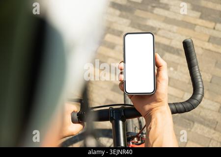 Male cyclist holding smartphone with white screen Stock Photo