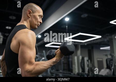 Athletic man doing dumbbell biceps curl strength training Stock Photo