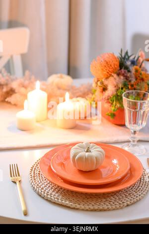 Thanksgiving day table setting with fall decorations of flowers in pumpkin. Stock Photo